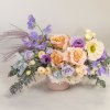 Pastel bouquet of roses, poppies, and purple blooms in a pink vase
