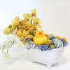 Yellow and white orchids in a white bowl with a small rubber duck