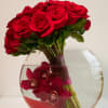 Red roses and dark red orchids arranged in a round glass vase