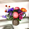 Colorful bouquet with pink, purple, and orange flowers in a dotted vase