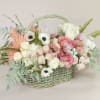 Pastel flower arrangement in a woven basket with pink and white blooms