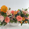 Coral and peach roses with orange poppies in a white bowl vase