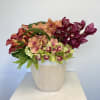 Mixed orchid arrangement in a light wood vase