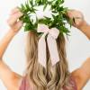 Woman wearing a green leaf crown with a pale pink ribbon