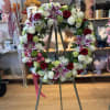 Circular floral wreath on an easel with red, white, and pink blooms