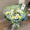 Bouquet of white daisies and yellow carnations wrapped in green paper