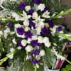 White lilies, roses, and purple blooms in a large standing spray
