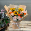 Bouquet of sunflowers, orange roses, and pale pink carnations wrapped in tan paper
