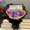 Bouquet of pink roses and purple hydrangea in black wrapping
