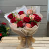 Bouquet of red and blush roses wrapped in cream paper with a gold ribbon