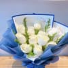 Bouquet of white roses wrapped in blue paper with a ribbon