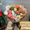 Bouquet of white daisies, roses, and pink carnations wrapped in brown paper