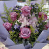 Bouquet of pink roses and purple flowers wrapped in lavender paper