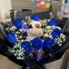 Blue roses arranged around a plush cow with baby’s breath and chocolates