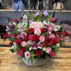 Large basket arrangement of red and pink roses with lilies and purple flowers