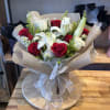 Bouquet of red roses and white lilies wrapped in beige paper