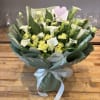 Bouquet of white calla lilies and yellow spray roses wrapped in green paper