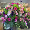Large mixed bouquet with pink roses, lilies, and purple flowers in containers