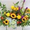 Bright mixed bouquet with sunflowers, yellow roses, and blue hydrangeas in a white box