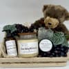 Gift basket with a teddy bear, candles, soap, lotion, scrub, and faux grapes