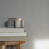 Lit candle in a glass jar beside its box on stacked books