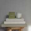 Eucalyptus candle in a glass jar beside its box on stacked books