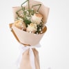 Peach roses wrapped in blush paper with a white ribbon