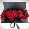Red roses arranged in a black presentation box with a ribbon