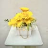 Yellow gerbera daisies in a white box with a gold chain handle