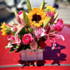 Bright bouquet of pink roses, lilies, and sunflowers in a white box