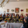 Group of women holding colorful floral arrangements in a gallery room