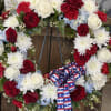 Red, white, and blue floral wreath with a patriotic ribbon bow
