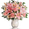 Pink lilies and roses arranged in a white vase