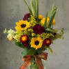 Bouquet of sunflowers and burgundy flowers in a glass vase with a plaid ribbon