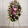 Large standing floral spray with pink, white, and purple flowers on a wooden easel