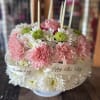 Pink carnations and white daisies arranged in a round birthday cake design