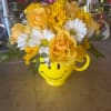 Yellow roses and white daisies in a smiley-face mug