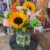 Sunflowers and pink mixed flowers arranged in a glass vase