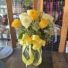 Yellow and white roses in a glass vase with a yellow ribbon