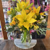Yellow lilies and small orange roses in a glass vase