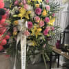 Large standing floral spray with pink and yellow flowers and a memorial ribbon