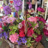 Basket of pink, purple, and red flowers with a woven handle