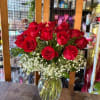 Red roses arranged in a clear glass vase with white baby's breath.