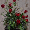 Red roses arranged in a low black container with curly branches
