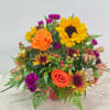 Mixed bouquet with sunflowers, orange roses, and purple blooms in a pink container