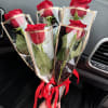 Four red roses wrapped in clear plastic with red ribbons