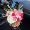 Pink and white rose bouquet in a wicker basket with greenery