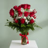 Red roses and baby's breath in a glass vase with a red ribbon
