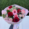 Bouquet of red roses, pink gerberas, and pale pink mums wrapped in pink paper