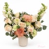 Peach and cream bouquet in a ribbed vase with tall white snapdragons